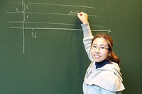 female mathematician draws a diagram on a blackboard